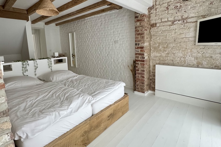 Holzbett im unteren Schlafzimmer vor Backsteinwand
