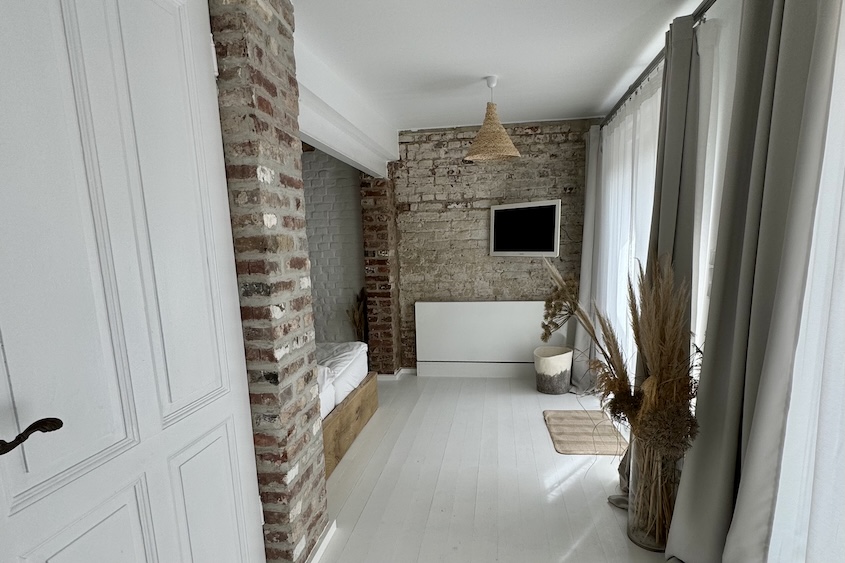 Ansicht des Schlafzimmers vom Schreibtisch hin zum Bett, rechts die Glasfront zum eigenen Innenhof