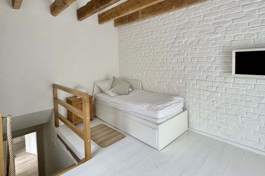 Bett im oberen Schlafzimmer vor weiß gestrichener Backsteinwand
