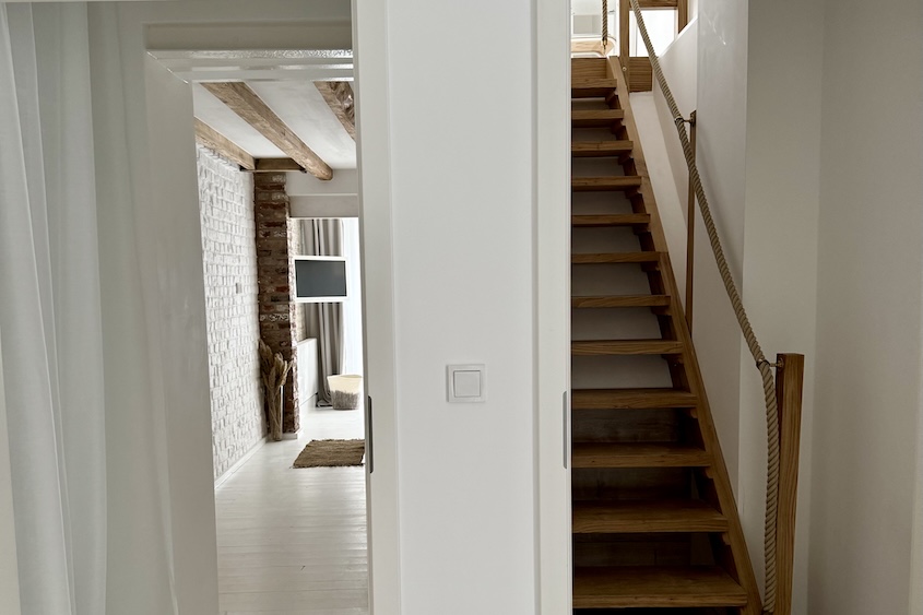 Blick Richtung Schlafräume, rechts die Holztreppe nach oben, links der Durchgang zum unteren Schlafzimmer